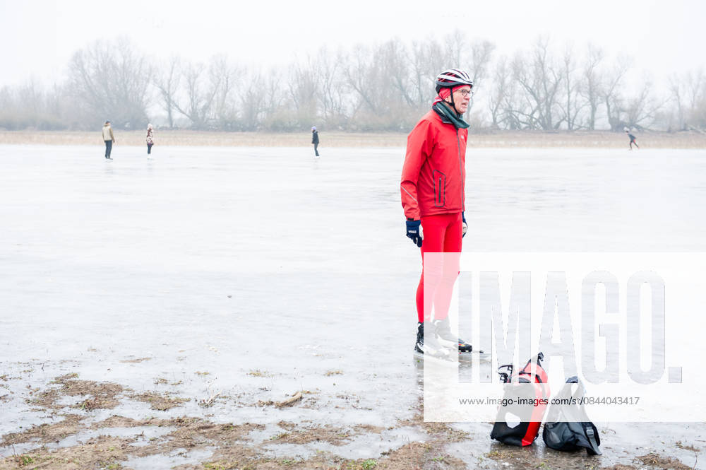 A man in red clothes is taking a break from skating on the ice lake. After several days of sub-zero temperatures during the night, the water of some lakes started to freeze over. People took the chance to skate on one of the frozen lakes close to the Dutch city of Nijmegen. It takes at least four whole days of below-freezing temperatures to form ice thats safe to walk and skate on, and that only applies to ponds or lakes with no currents. Nijmegen Netherlands - ZUMAs197 20251227_aab_s197_059
