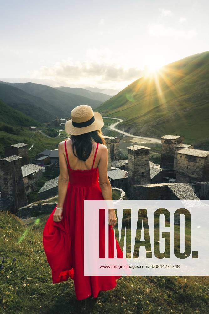 Reisende, hübsche Frau im roten Maxisommerkleid, genießt den Wellness Lifestyle bei Sonnenuntergang in den Bergen in Ushguli, Georgia, mit malerischer Tallandschaft Traveler pretty woman in red maxi sundress enjoying mountain sunset wellness lifestyle in Ushguli Georgia with scenic valley landscape