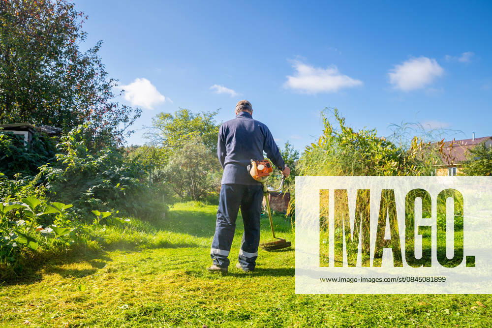 Senior man uses grass trimmer to cut overgrown lawn in his backyard Chelyabinsk, Chelyabinsk Oblast, Russia CR_STCJ260106-1921656-01 ,model released, Symbolfoto