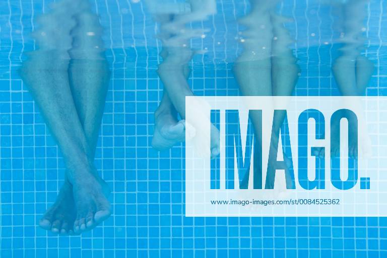 Family soaking feet in pool, underwater view