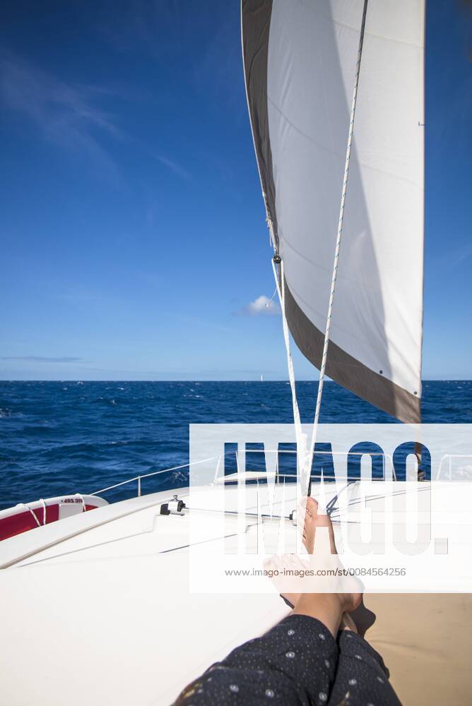 Low section view with feet of woman sunbathing on sailboat sailing in sea, Bourg de Saintes Iles de Saintes Guadeloupe BRCA003062 model released Symbolfoto