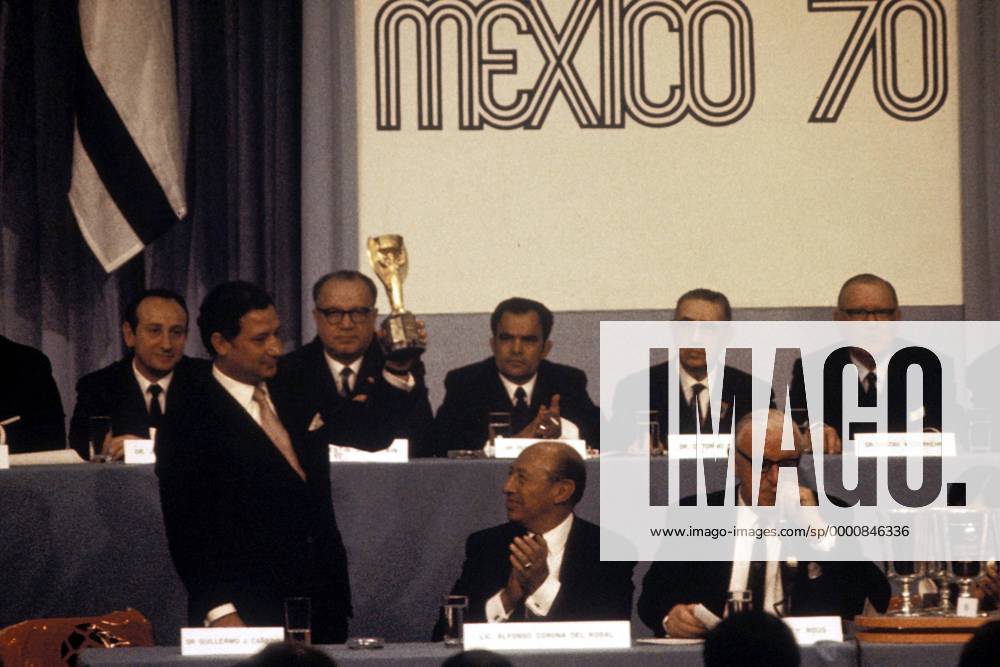 FIFA-Vizepräsident Guillermo Caneda (li.) präsentiert während der Gruppenauslosung den Coupe Jules Rimet, der Bürgermeister von Mexico-City Alfonso Corona del Rosal (Mitte, beide Mexiko) applaudiert, daneben FIFA-Präsident Sir Stanley Rous (England) Fußball WM Herren Auslosung der Gruppen für die Weltmeisterschaft 1970, Versammlung, Sitzung, Tagung, auslosen Gruppe Aufnahmedatum geschätzt Mexico-Stadt, Weltmeisterschaftspokal