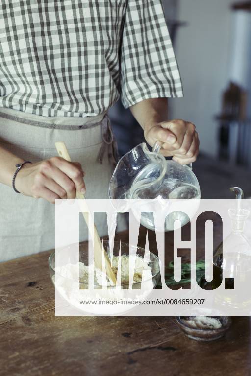Young woman in kitchen preparing dough for fresh chickpea cake model released Symbolfoto ALBF00446