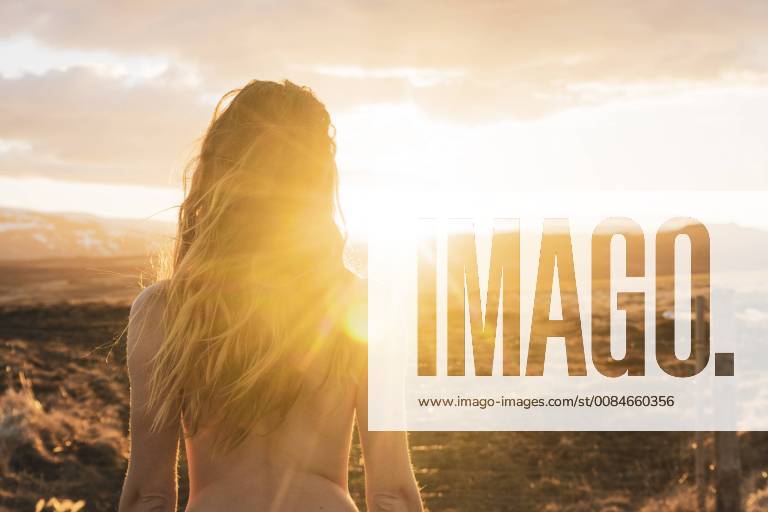 Iceland, rear view of naked young woman at sunset model released Symbolfoto KKAF01105