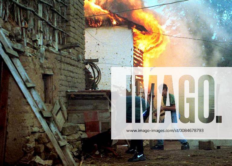Zegra, YUG - Ethnic Albanians free a dog who was tied up near a burning house in the village of Zegra, Kosovo on June 24, 1999. The Serbs fled their village with an escort of American NATO troops while Albanians looted and burned their property. Zegra YUG - ZUMAm67_ 19990624_zaf_m67_001