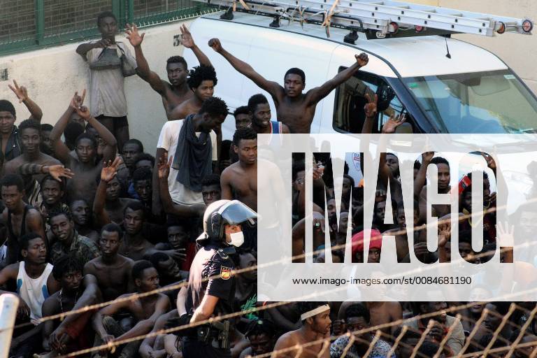 Several migrants celebrate next to a Spanish policeman in Ceuta, Spanish enclave in northern Africa, after they managed to jump the border fence between Spain and Morocco, 26 July 2018. Some 400 migrants reached Spain in a mass jump of the Spanish border early morning despite the holding operation by Spanish and Moroccan security forces. More than a dozen of Spanish Civil Guard officers and five immigrants were injured as security forces sources said that the migrants acted violently. Some 400 migrants managed to jump Spanish border fence in Ceuta !ACHTUNG: NUR REDAKTIONELLE NUTZUNG!