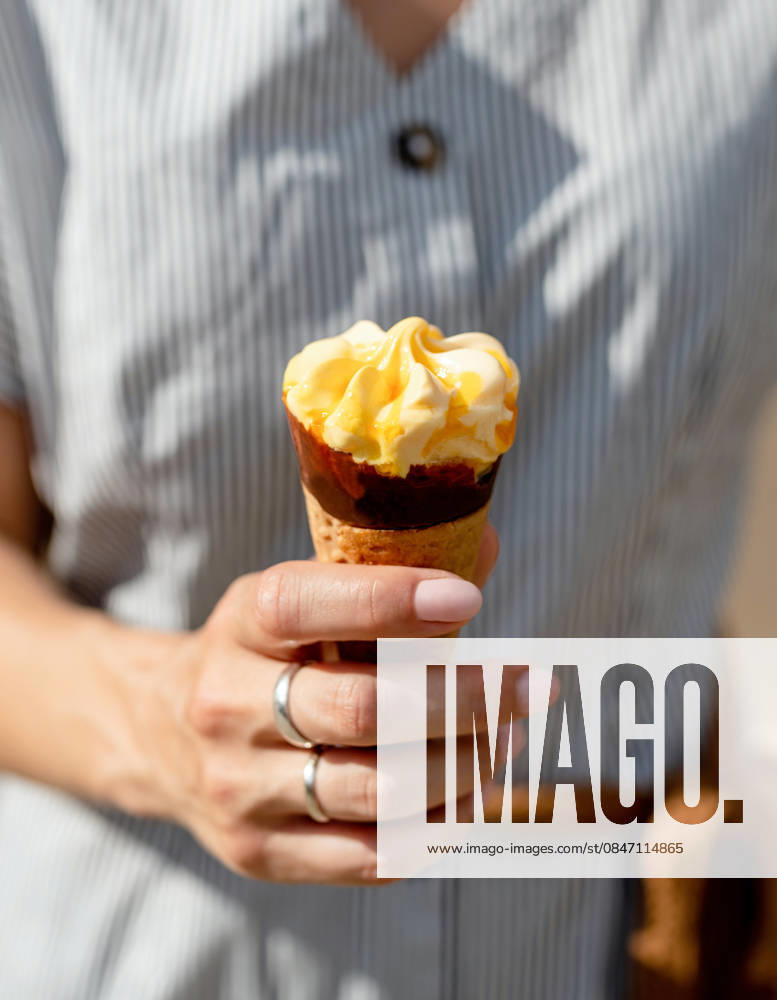 Frau mit fruchtigem Eis in den Händen Woman hand holding ice cream cone outdoors (License=RF)