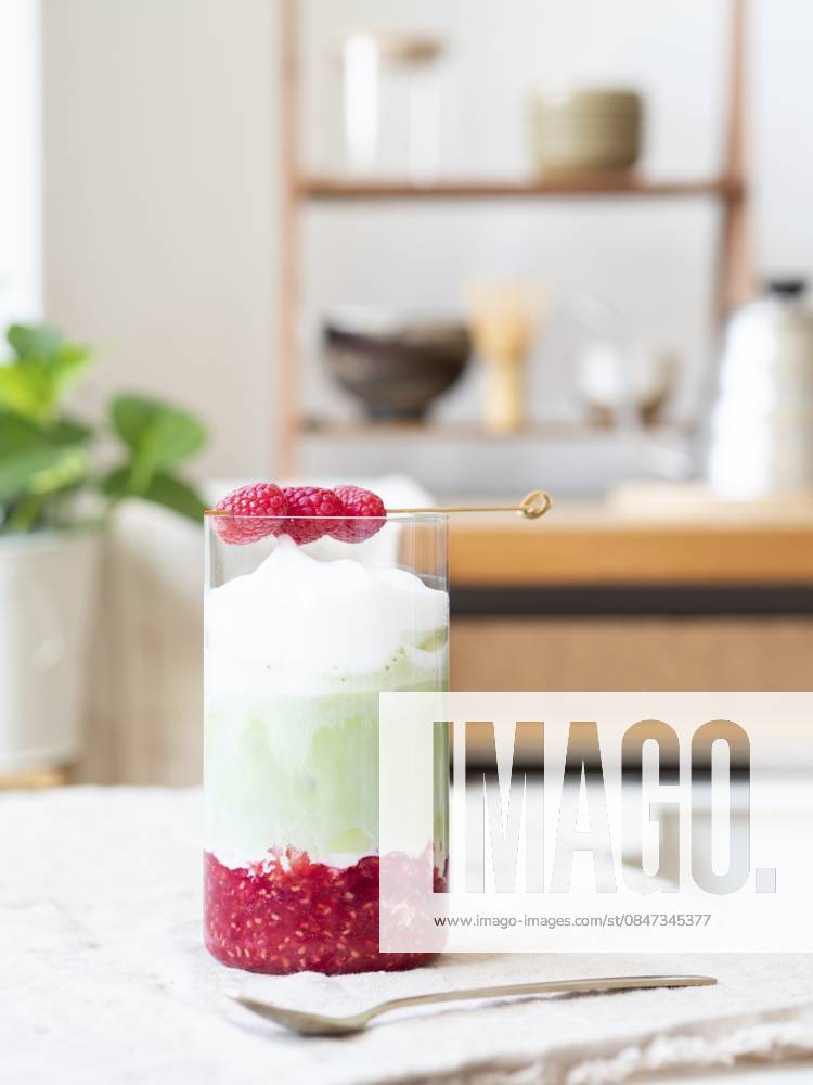Erfrischender geschichteter Iced Matcha Latte mit Himbeerpüree und schaumigem Topping Refreshing layered iced matcha latte with raspberry puree and foamy topping