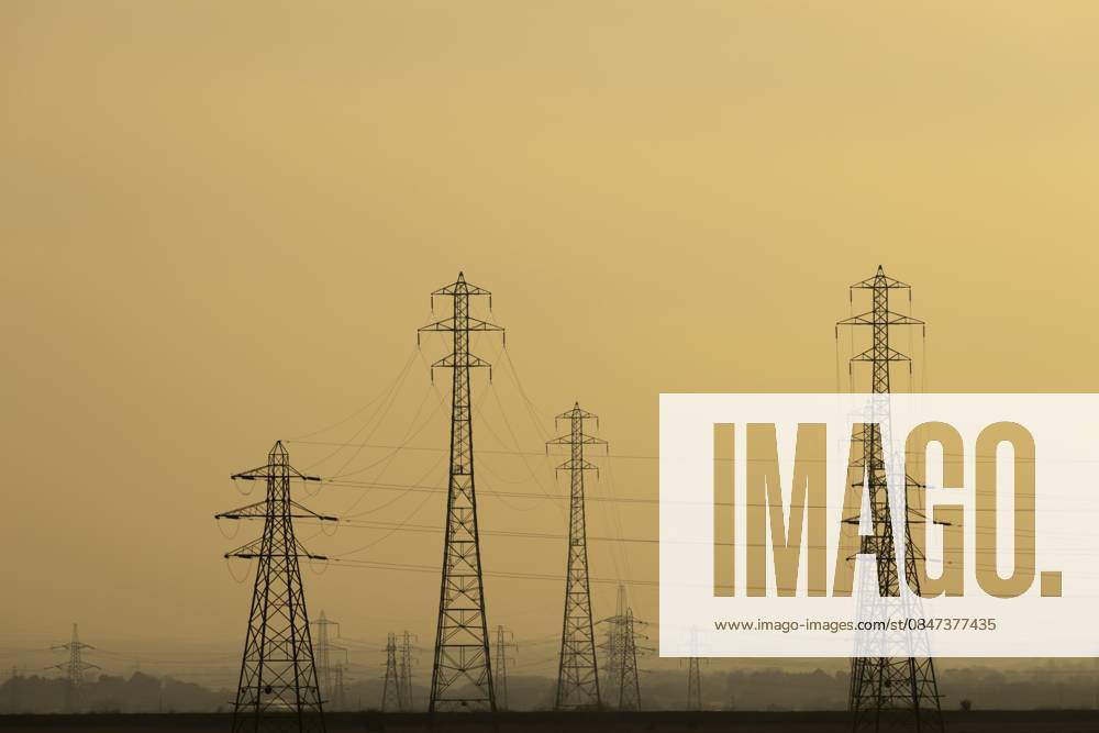 Silhouette von Strommasten und Stromleitungen bei Sonnenuntergang, England, Großbritannien Electricity pylons and power lines silhouette at sunset, England, United Kingdom