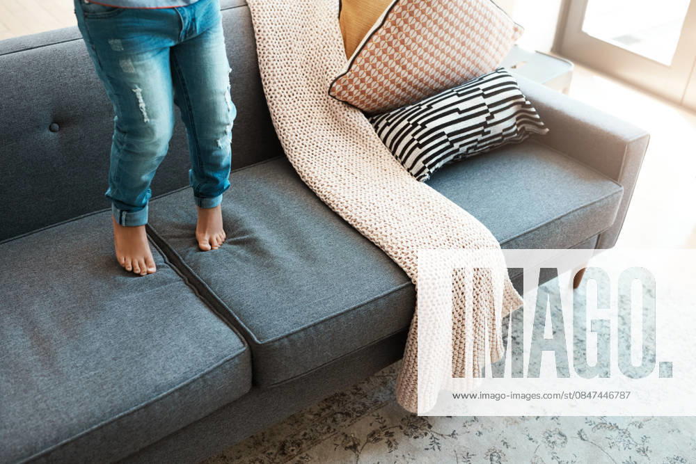 Home, legs and kid on sofa, jumping and playing with fun for development, break and tiptoe. Apartment, child growth and boy with adhd on couch, activity and naughty in afternoon, energy and game. model released property released