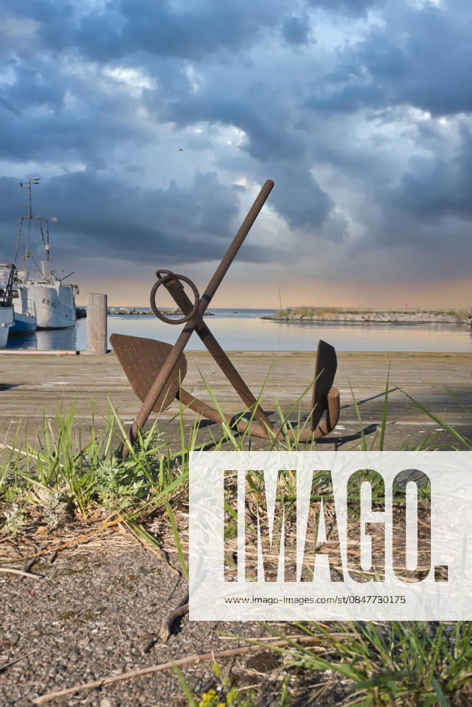 Rostiger Anchor at Port before a Dramatic Sky with Coastal scenery 1132203583