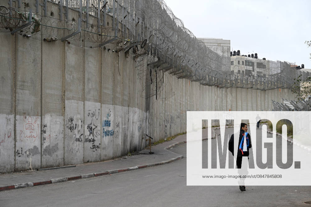 A Palestinian walks beside the Israeli separation wall dividing Al-Ram, West Bank from Beit Hanina, near Jerusalem, on Tuesday, February 17, 2026. Extended families are separated by the wall that cuts through a neighborhood where Palestinians once moved freely. JER2026021707 DEBBIExHILL