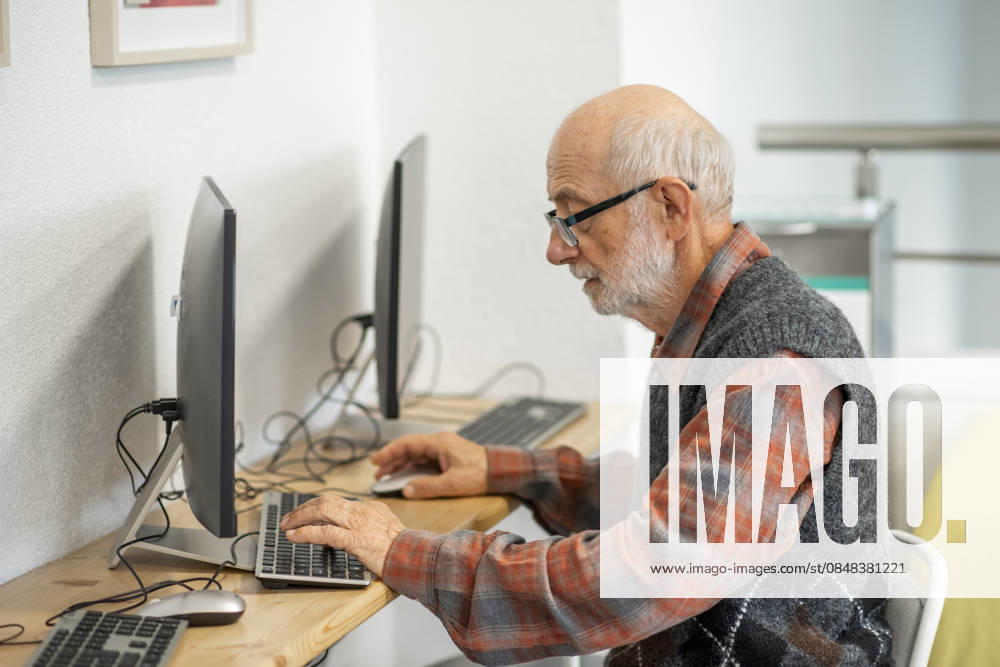 Senior man working on computer at desk. Focused senior man working on computer at desk. model released