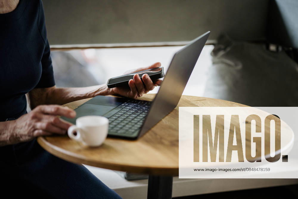 Person using laptop and smartphone at café table with coffee model released, Symbolfoto property released, KNSF12169