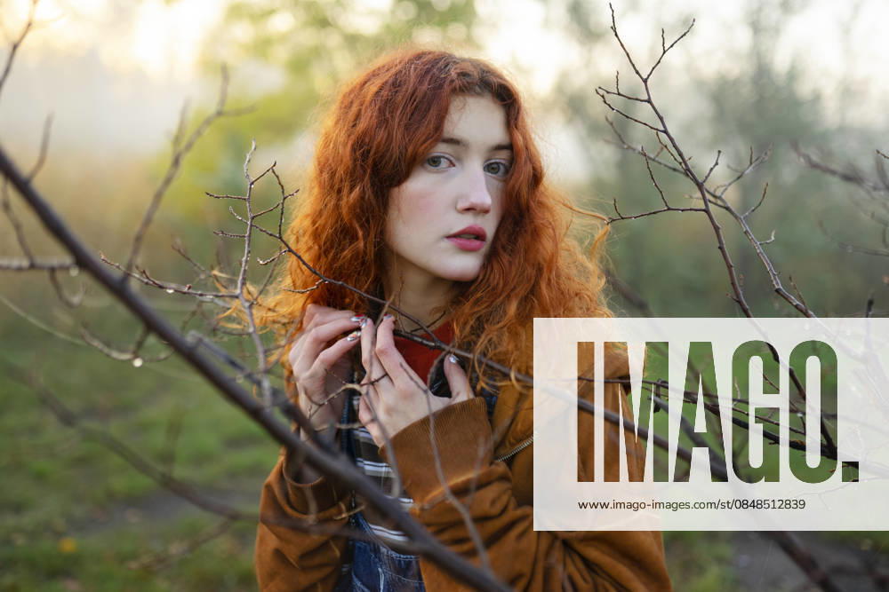 Red-haired woman in orange hoodie and denim overall in foggy forest model released, Symbolfoto, VCF01242
