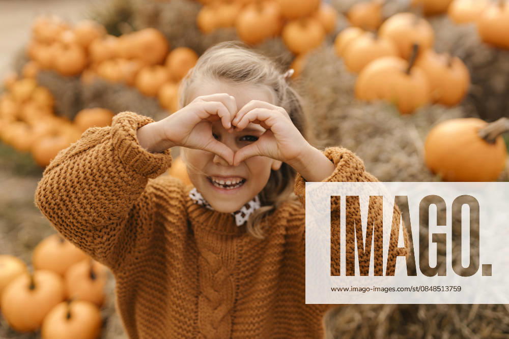 Child making heart gesture in pumpkin patch during autumn harvest model released, Symbolfoto, VIVF01728