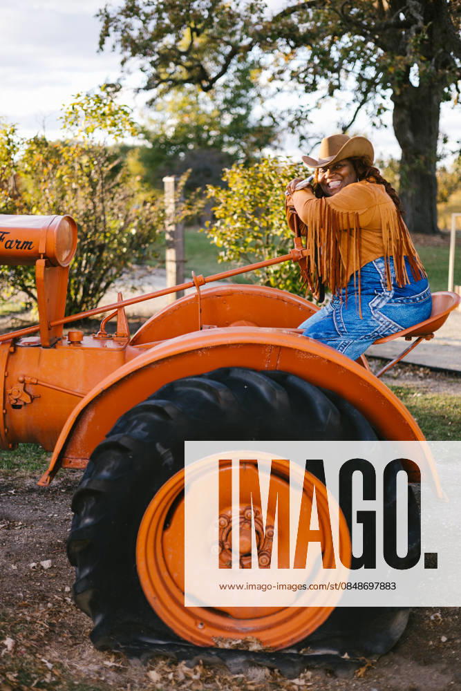 Black woman on orange tractor in cowboy hat and jacket Gurnee, Illinois, United States CR_WVNP260219-1960149-01 ,model released, Symbolfoto