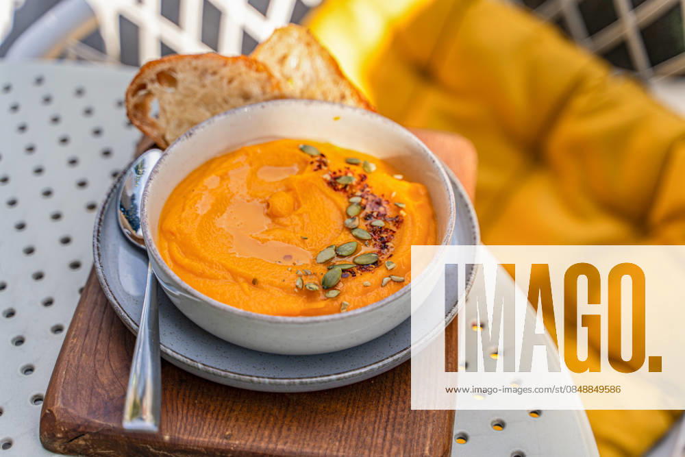 Creamy autumnal pumpkin soup garnished with seeds A warm bowl of creamy pumpkin soup garnished with seeds makes the perfect autumnal treat. Served with crusty bread, this dish embodies the essence of cozy fall flavors. Model Released AnnaBogush_ID33621_1170754_006