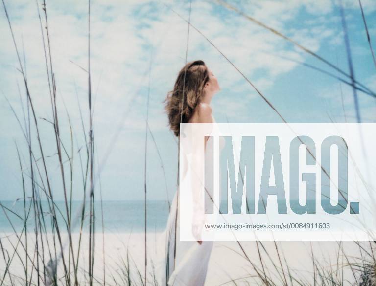 Woman standing at the beach with arms back, side view