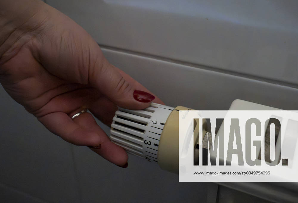 A hand adjusts the thermostat on a radiator in an apartment Symbolic image on the subject of heating, saving energy and rising energy costs in the home Gummersbach, North Rhine-Westphalia, Germany 06 03 2026