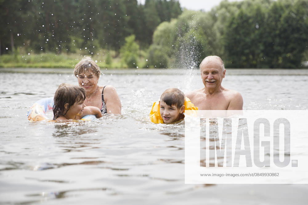 Familie auf Urlaub splashen in einem See. Glückliche Großeltern mit Enkelkindern genießen Sommerurlaubdie und spielt im Fluss. Family on vacation splashing in a lake. Happy grandparents with grandchildren enjoying summer vacationthe and plays in the river. (License=RF) ,model released, Symbolfoto