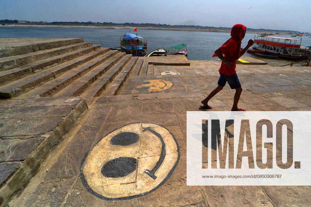 A man walks past a street mural depicting a smiley emoji. Varanasi India - ZUMAs197 20260228_aab_s197_064
