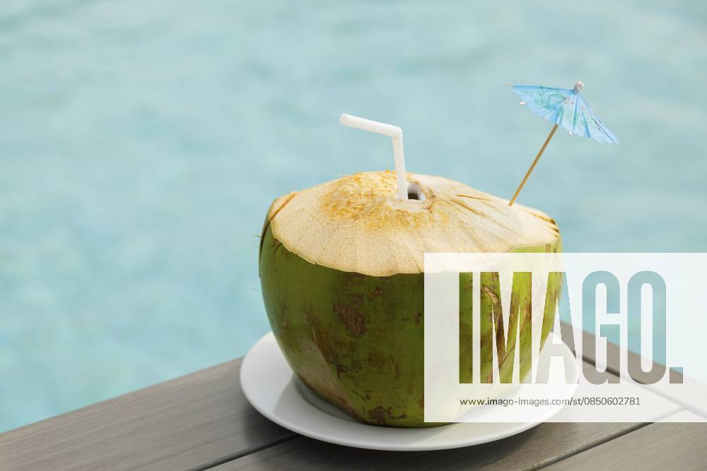 Frisches Kokosnussgetränk auf dem Tisch neben dem Pool Fresh coconut drink on the table beside the swimming pool