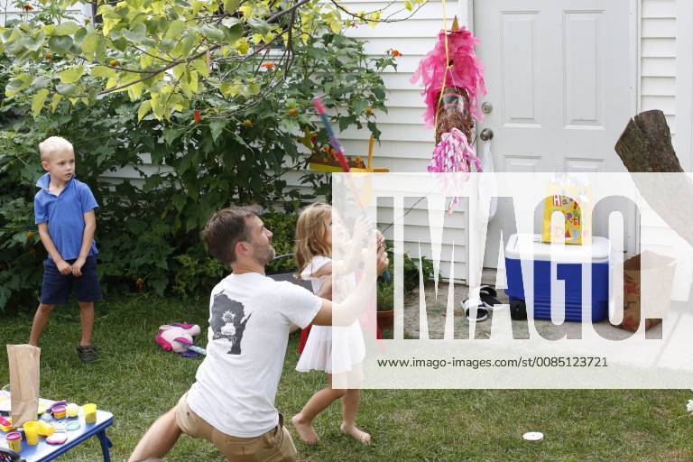 Mid adult father playing with little daughter during birthday party in front or back yard, Oak Park IL United States ROBE000567 model released Symbolfoto