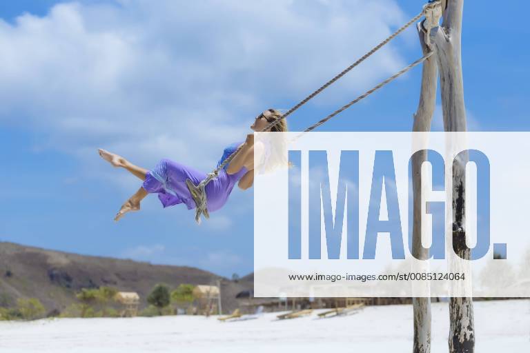 Side view of woman in purple dress on swing on beach, Kuta, Lombok, Indonesia, Kuta Lombok Indonesia TRKO020278 model released Symbolfoto