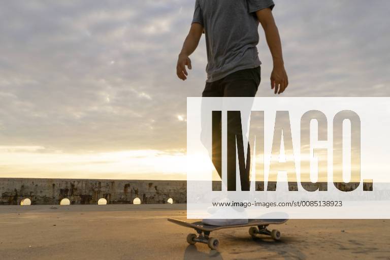 Young Chinese man skateboarding at sunsrise near the beach model released Symbolfoto AFVF00735