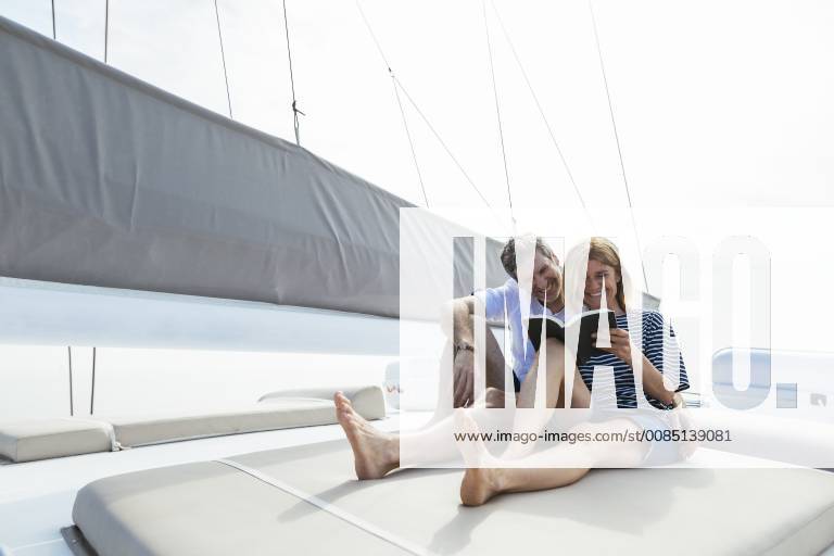 Couple sitting on deck of catamaran, relaxing, woman reading book model released Symbolfoto property released EBSF02609