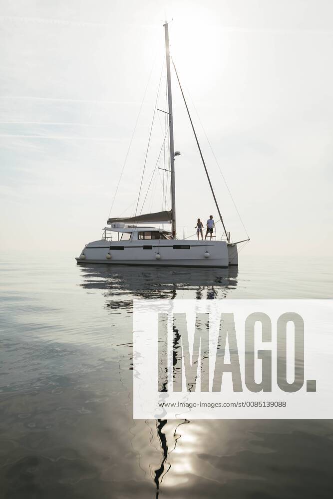 Couple setting off for a sailing trip on a catamaran model released Symbolfoto property released EBSF02664