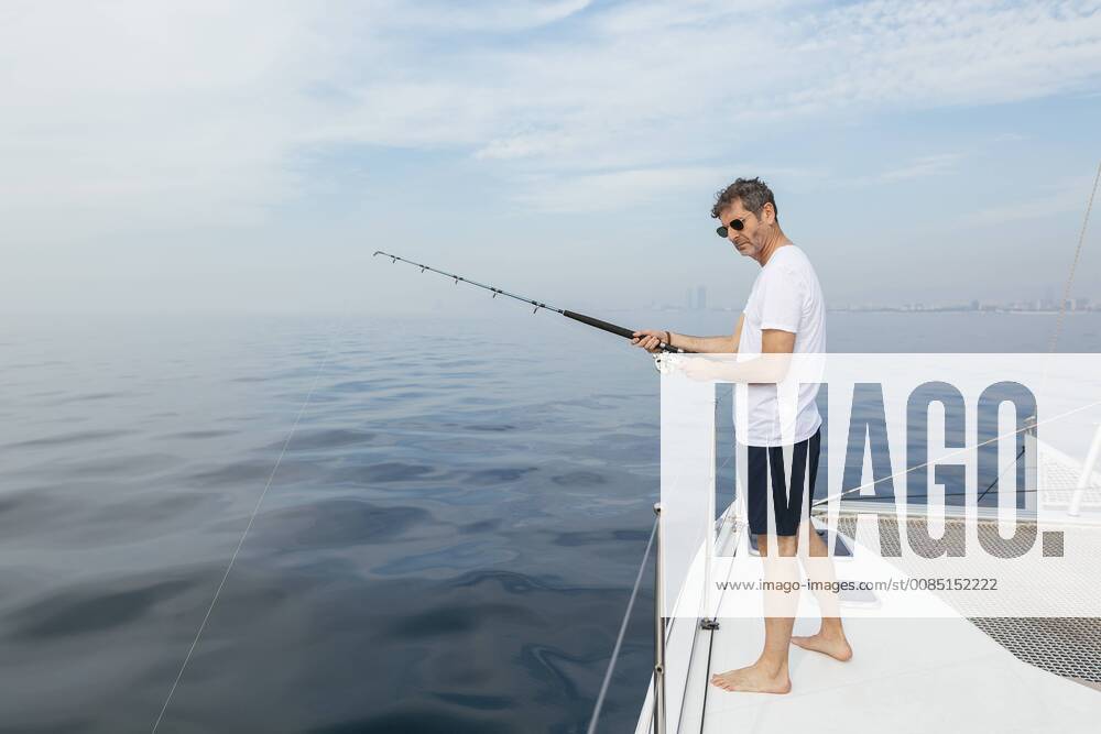 Mature man standing on catamaran, fishing model released Symbolfoto property released EBSF02576