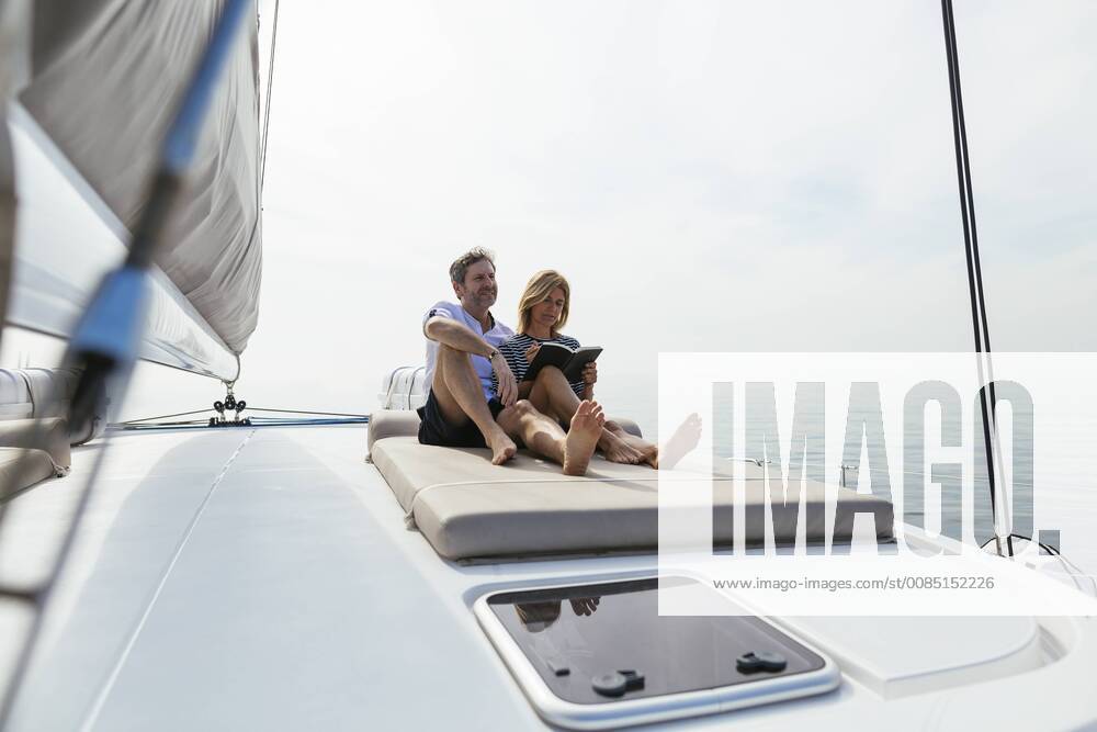 Couple sitting on deck of catamaran, relaxing, woman reading book model released Symbolfoto property released EBSF02603