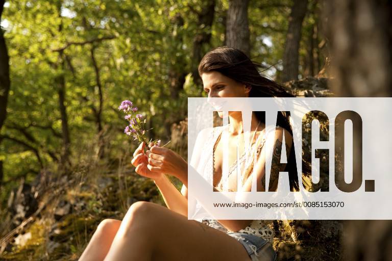 Young woman in forest binding bunch of flowers model released Symbolfoto MFRF00965