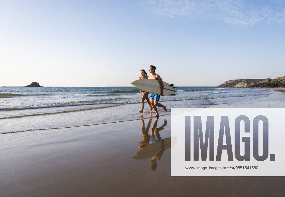 Surfers running with surfboard along the beach on a sunny summer day model released, Symbolfoto, UUF36530