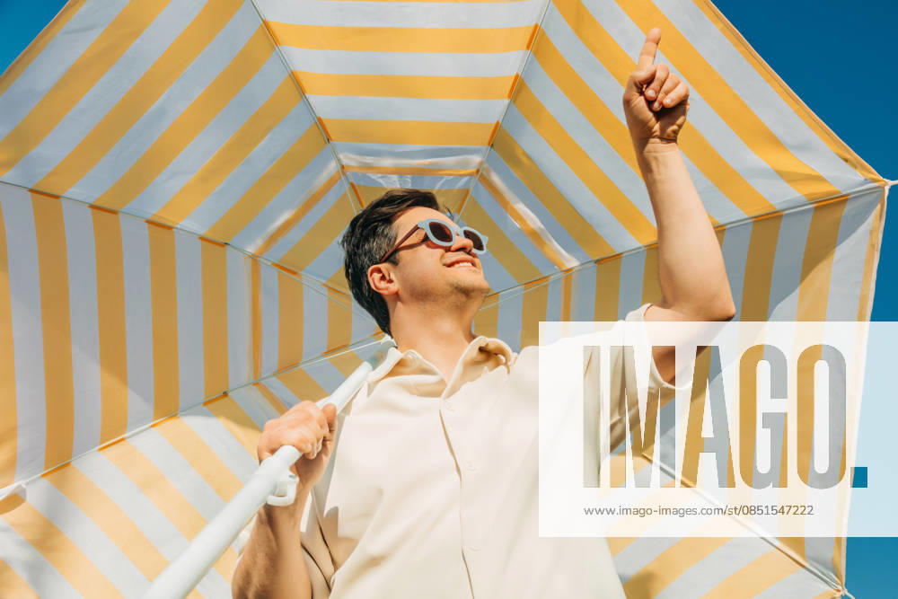 Smiling man in sunglasses under striped umbrella on sunny summer day model released, Symbolfoto, VSNF04729