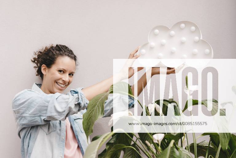 Smiling woman holding cloud over house plant model released Symbolfoto property released KNSF04083