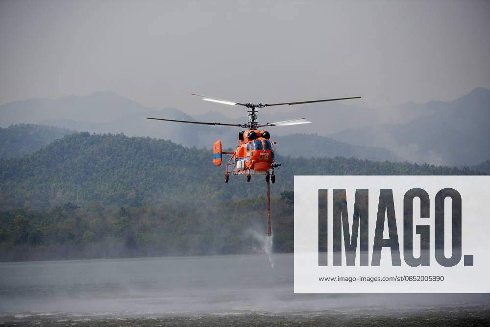 A helicopter performs water pickup operations over a reservoir in Chiang Mai, northern Thailand, as part of aerial firefighting efforts against ongoing wildfires. A KA-32 helicopter from the Department of Disaster Prevention and Mitigation skims the water surface to collect water before heading to fire-affected forest areas amid hazy conditions caused by smoke and rising PM2.5 pollution. Chiang Mai Thailand - ZUMAs197 20260327_aaa_s197_321