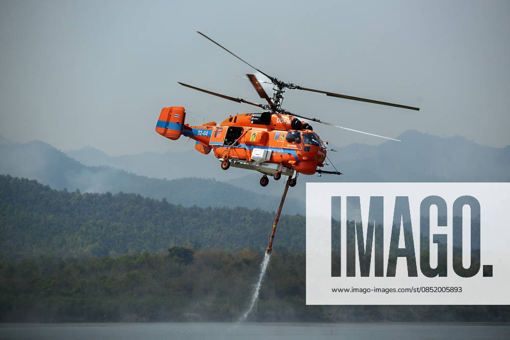 A helicopter performs water pickup operations over a reservoir in Chiang Mai, northern Thailand, as part of aerial firefighting efforts against ongoing wildfires. A KA-32 helicopter from the Department of Disaster Prevention and Mitigation skims the water surface to collect water before heading to fire-affected forest areas amid hazy conditions caused by smoke and rising PM2.5 pollution. Chiang Mai Thailand - ZUMAs197 20260327_aaa_s197_328