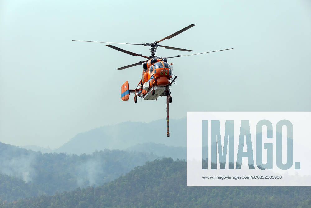A KA-32 helicopter from the Department of Disaster Prevention and Mitigation conducts aerial firefighting operations over mountainous forest areas in Chiang Mai, northern Thailand, carrying a water bucket while flying through smoke-filled valleys as authorities battle ongoing wildfires and severe PM2.5 air pollution. Chiang Mai Thailand - ZUMAs197 20260327_aaa_s197_343