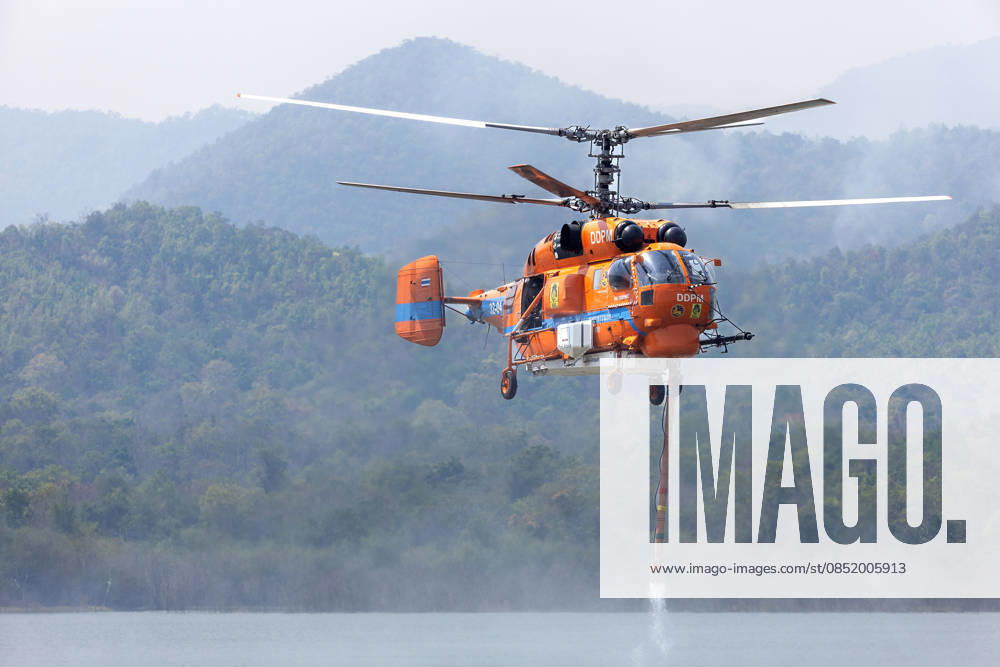 A helicopter performs water pickup operations over a reservoir in Chiang Mai, northern Thailand, as part of aerial firefighting efforts against ongoing wildfires. A KA-32 helicopter from the Department of Disaster Prevention and Mitigation skims the water surface to collect water before heading to fire-affected forest areas amid hazy conditions caused by smoke and rising PM2.5 pollution. Chiang Mai Thailand - ZUMAs197 20260327_aaa_s197_342
