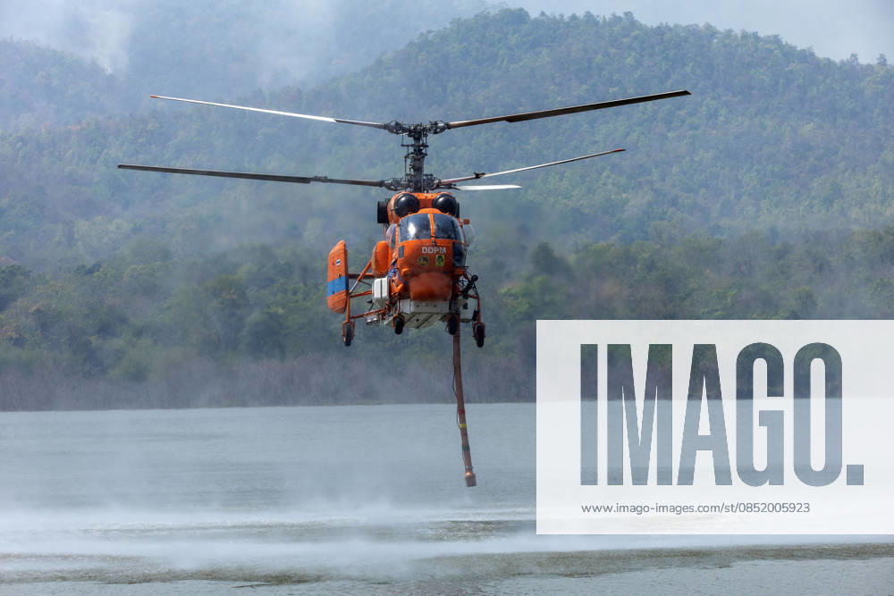 A helicopter performs water pickup operations over a reservoir in Chiang Mai, northern Thailand, as part of aerial firefighting efforts against ongoing wildfires. A KA-32 helicopter from the Department of Disaster Prevention and Mitigation skims the water surface to collect water before heading to fire-affected forest areas amid hazy conditions caused by smoke and rising PM2.5 pollution. Chiang Mai Thailand - ZUMAs197 20260327_aaa_s197_369
