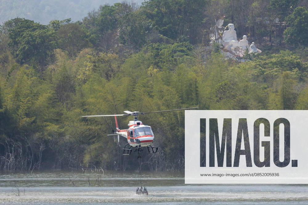 A helicopter performs water pickup operations over a reservoir in Chiang Mai, northern Thailand, as part of aerial firefighting efforts against ongoing wildfires. An AS350 helicopter from the Ministry of Natural Resources and Environment skims the water surface to collect water before heading to fire-affected forest areas amid hazy conditions caused by smoke and rising PM2.5 pollution. Chiang Mai Thailand - ZUMAs197 20260327_aaa_s197_379
