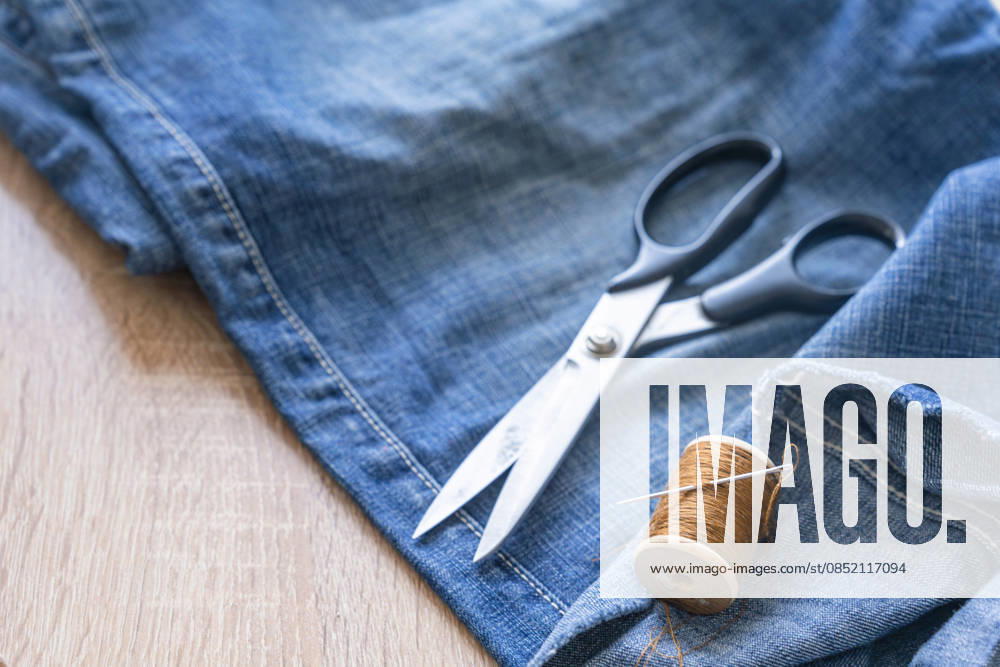 IMAGO Creative, Lifestyle, Freizeit, Hobby, Handarbeit, Nähen #2 Nähwerkzeuge und brauner Faden auf blauen Denim für das Mähen, Schneidern und Upcycling von alten Jeans, Diy Reparatur, Handwerk und nachhaltige Mode Projekt. Tailoring blauen Denim Jeans mit Schere und Gewinde Sewing tools and brown thread on blue denim for mending, tailoring and upcycling old jeans, diy repair, craft and sustainable fashion project. Tailoring blue denim jeans with scissors and thread (License=RF)