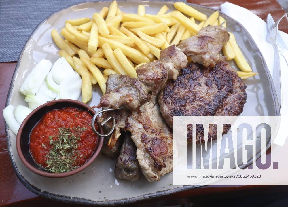 Leckerer kroatischer Grillteller mit Pommes Frites, Zwiebeln, Ajvar, Hacksteak, Cevapcici, Steak und Spießchenfleisch Delicious Croatian grill plate with french fries, onions, ajvar, minced steak, cevapcici, steak and skewer meat
