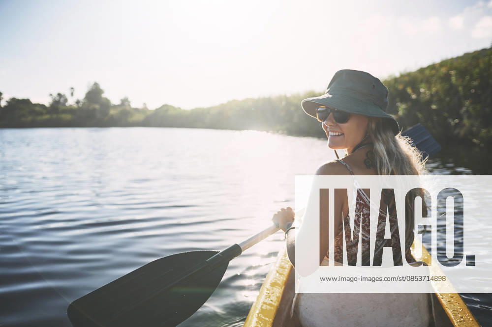 Canoe, happy and woman in nature for lake, summer vacation and adventure on holiday in countryside. Female person, rowing journey and smile on boat with paddle on river for travel and space outdoor. model released property released