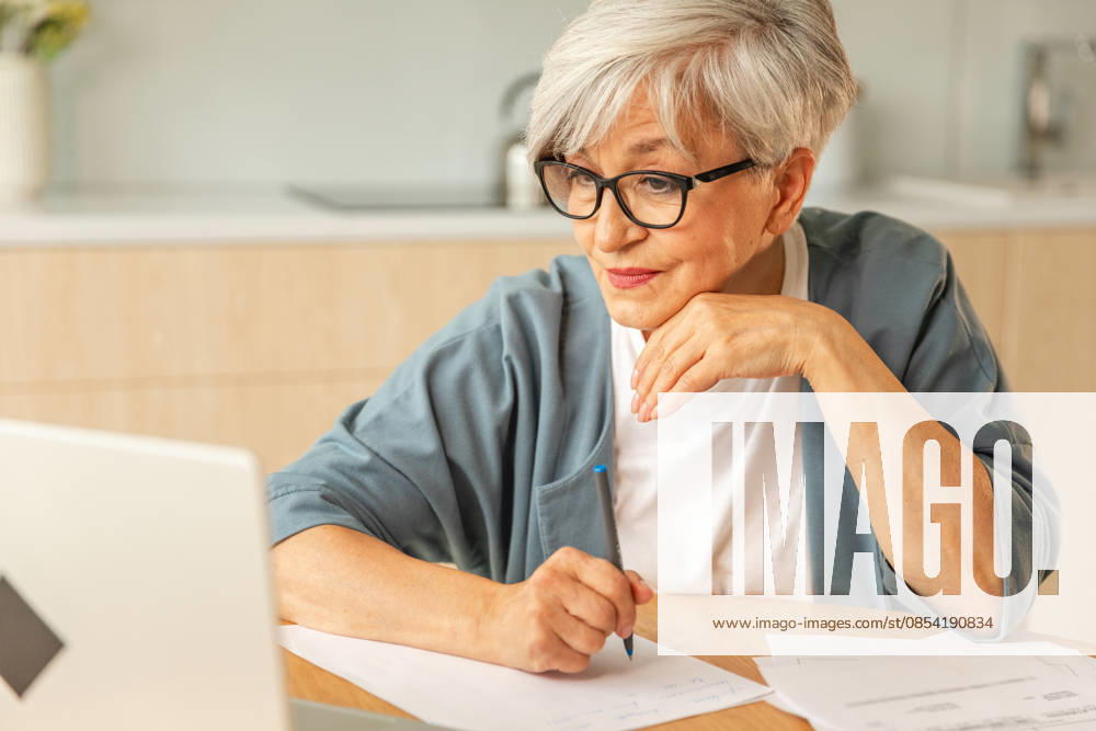 Online-Bildungskurse Webinar-Konzept. Middle aged senior Frau mit Laptop-Computer schreiben Notizen. Fokussierte reife alte Frau genießt Online-Studium von zu Hause schriftliche Aufzeichnungen tun Online-Arbeit. Online education courses webinar concept. Middle aged senior woman using laptop computer writing notes. Focused mature old woman enjoying studying online from home written records doing online work (License=RF) ,model released, Symbolfoto
