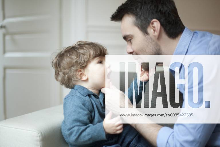 Father examining toddler son s teeth, portrait
