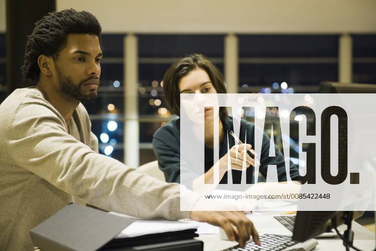 Colleagues working on project together in office at night